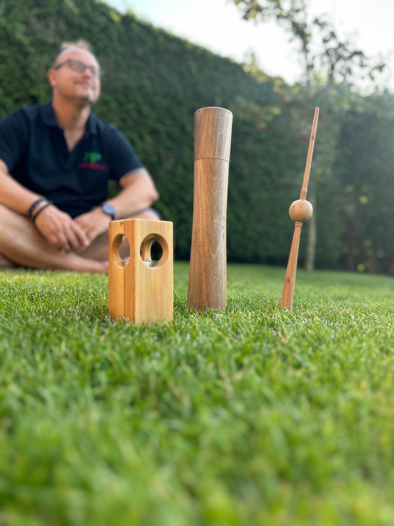 Marco Paul im Garten mit gedrechselten Holzobjekten